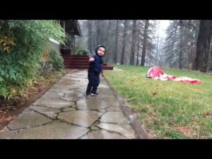 Bebé sufre tierna caída al jugar bajo la lluvia (VIDEO)